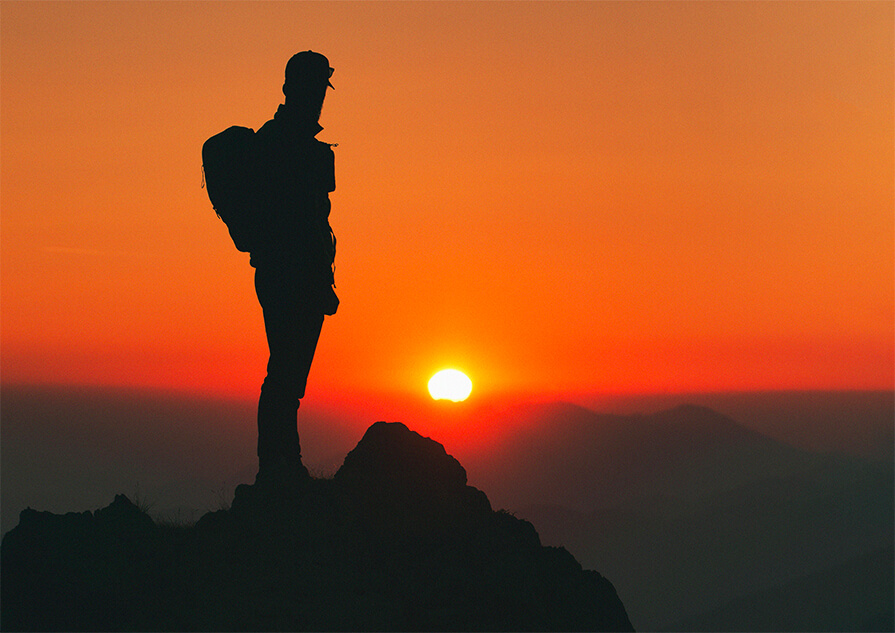 Photographie de la silhouette d’un randonneur devant le coucher de soleil